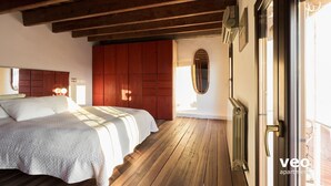 A bedroom with a wooden floor, a bed with a white bedspread, a red wardrobe, and a radiator. - Ibarra Terrace. Top-floor duplex with Cathedral views, Santa Cruz (Sevilla)