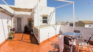 A rooftop terrace with a table and chairs, a small garden area with potted plants, and a view of the cityscape. - Ibarra Terrace. Top-floor duplex with Cathedral views, Santa Cruz (Sevilla)