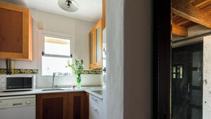 A kitchen with wooden cabinets, a microwave, and a window. - Ibarra Terrace. Top-floor duplex with Cathedral views, Santa Cruz (Sevilla)