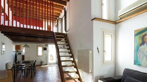 A spacious living area with a wooden staircase, a dining table, and a sofa. - Ibarra Terrace. Top-floor duplex with Cathedral views, Santa Cruz (Sevilla)