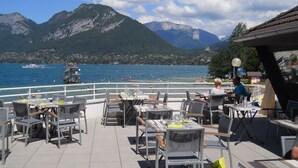 An outdoor dining area with tables and chairs, overlooking a lake with mountains in the background. - T3. 2 Bed Apart Private Garden, 200m to beach. super fast wifi. cheap bikes (Saint-Jorioz)
