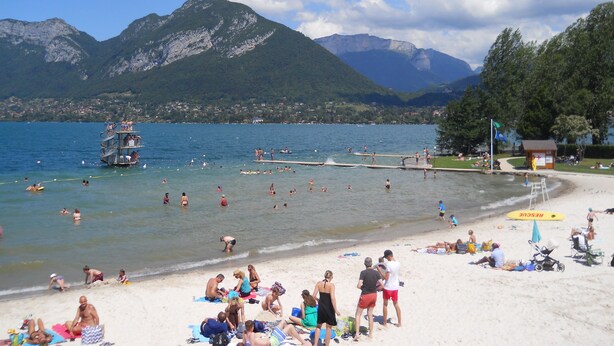 A beach with people sunbathing and swimming, a lifeguard tower, and mountains in the background. - T3. 2 Bed Apart Private Garden, 200m to beach. super fast wifi. cheap bikes (Saint-Jorioz)