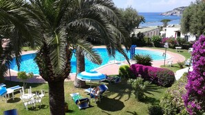 A pool area with lounge chairs and umbrellas, surrounded by palm trees and purple flowers. - relax in the green near the sea and from the center of Forio (Forio)