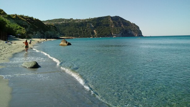 A beach with clear turquoise water, a rocky outcrop, and a hilly backdrop. - relax in the green near the sea and from the center of Forio (Forio)