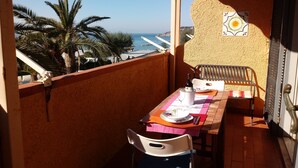 A balcony with a table set for two, overlooking a beach with palm trees and the sea. - relax in the green near the sea and from the center of Forio (Forio)