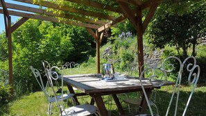Eine hölzerne Pergola im Freien mit Tisch und Stühlen.