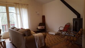 Ein gemütliches Wohnzimmer mit einer Couch, einem Sessel, einem Teppich und einem Kamin.