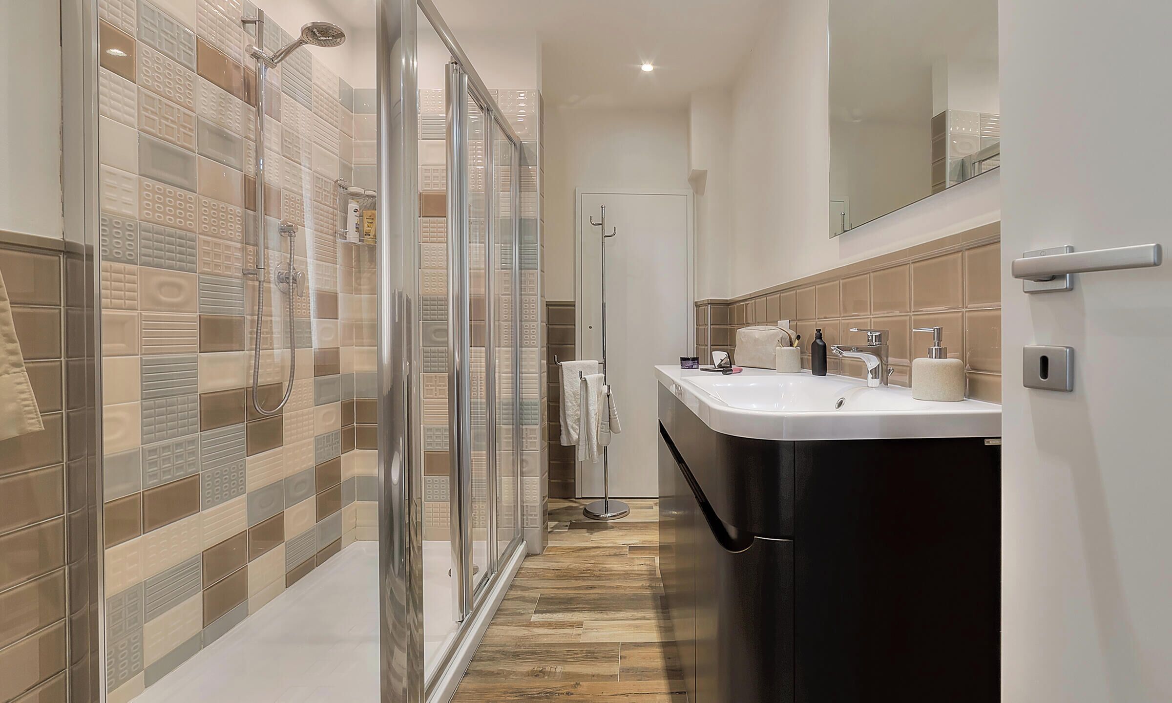 A modern bathroom with a glass shower enclosure, a white sink, and a mirror above it.