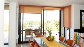 A modern dining area with a long table, orange chairs, and a yellow tablecloth. - Luxury apartment with beautiful views, private pool and beach access (Portocolom)