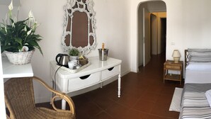 Un dormitorio con una cama, mesitas de noche, un aparador, un espejo y una planta en maceta.