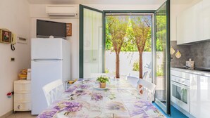 Una cocina compacta con refrigerador, horno y una mesa de comedor con sillas.