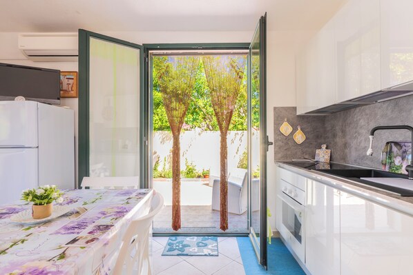 A modern kitchen with a large window, a dining area with a table, and a view of the garden.