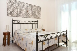 A neatly made bed with a patterned bedspread, a decorative metal headboard, and two bedside tables with lamps.