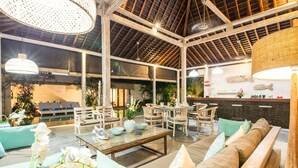 Eine großzügige Lobby mit hoher Decke, Holzbalken und einer Sitzecke mit Sofas und Sesseln.