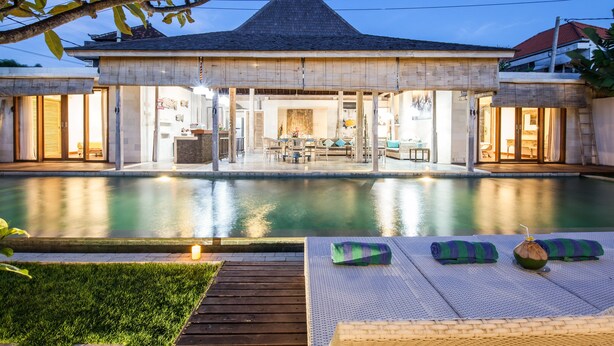 Ein modernes Haus mit Swimmingpool, einer überdachten Außenlounge und einem hellen Innenraum.