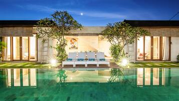 Ein modernes Haus mit Swimmingpool, einer überdachten Außenlounge und einem großen Wandgemälde.