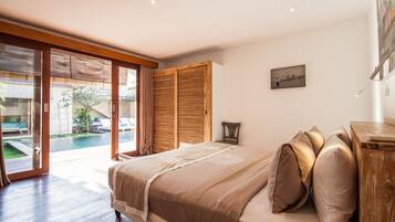 Ein Schlafzimmer mit einem großen Bett, einem Holzkopfteil und Blick auf einen Pool und Außenbereich.