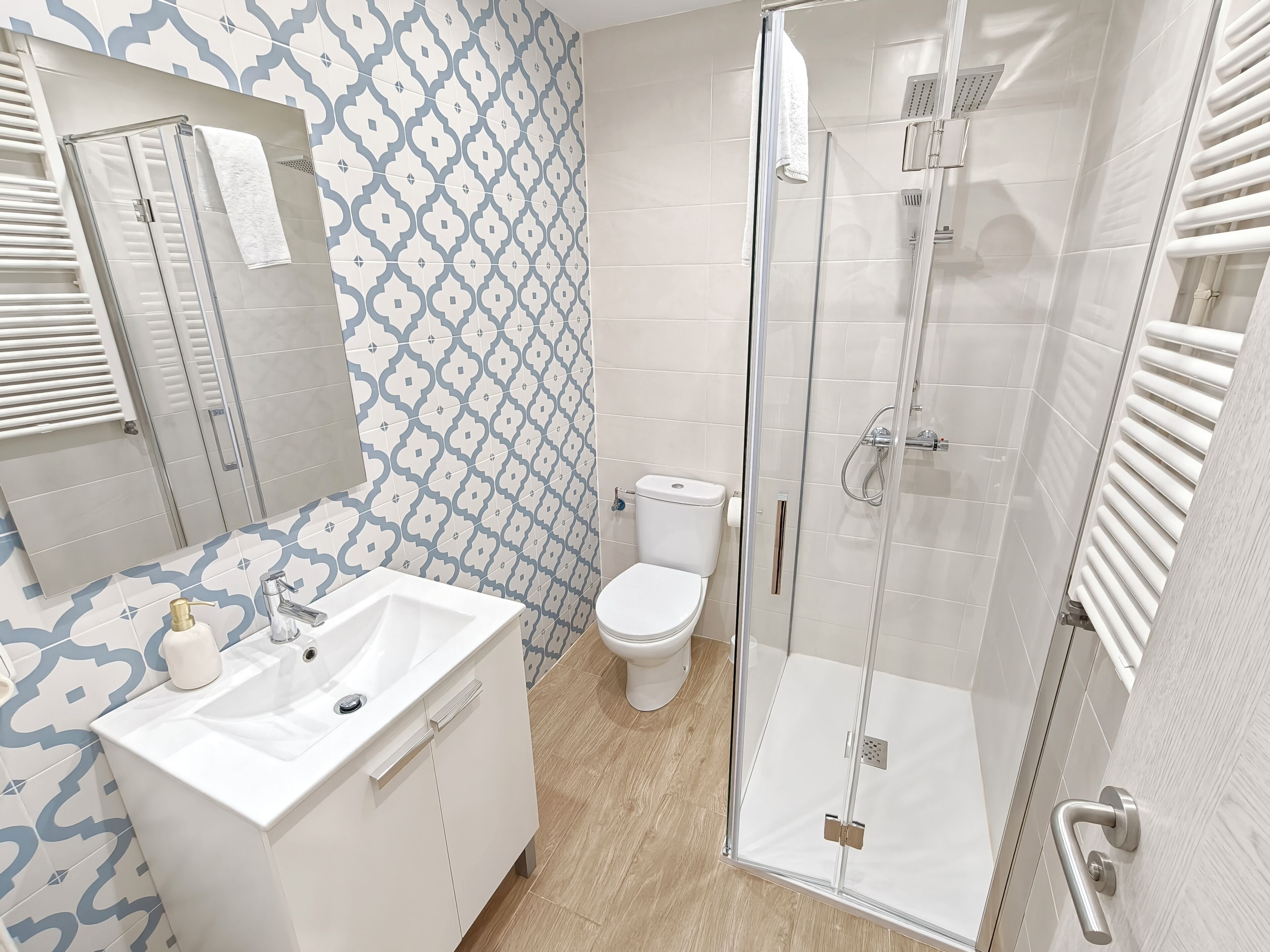 A modern bathroom with a glass-enclosed shower, a white sink, and a toilet.