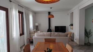 A modern living room with a wooden dining table, a sofa, a TV, and a fireplace.