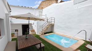 A pool area with a wooden table and chairs, a small staircase, and a white wall.
