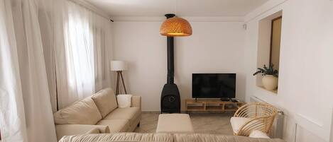 A living room with a sofa, a television, a lamp, a fireplace, and a wicker chair.