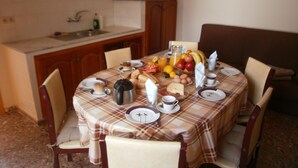A dining area with a table set for four, featuring a checkered tablecloth, plates, cups, and a variety of food items including fruits and bread. - Traditional Canarian Finca in Las Lajas, Icod de los Vinos, 4 persons (Icod de los Vinos)