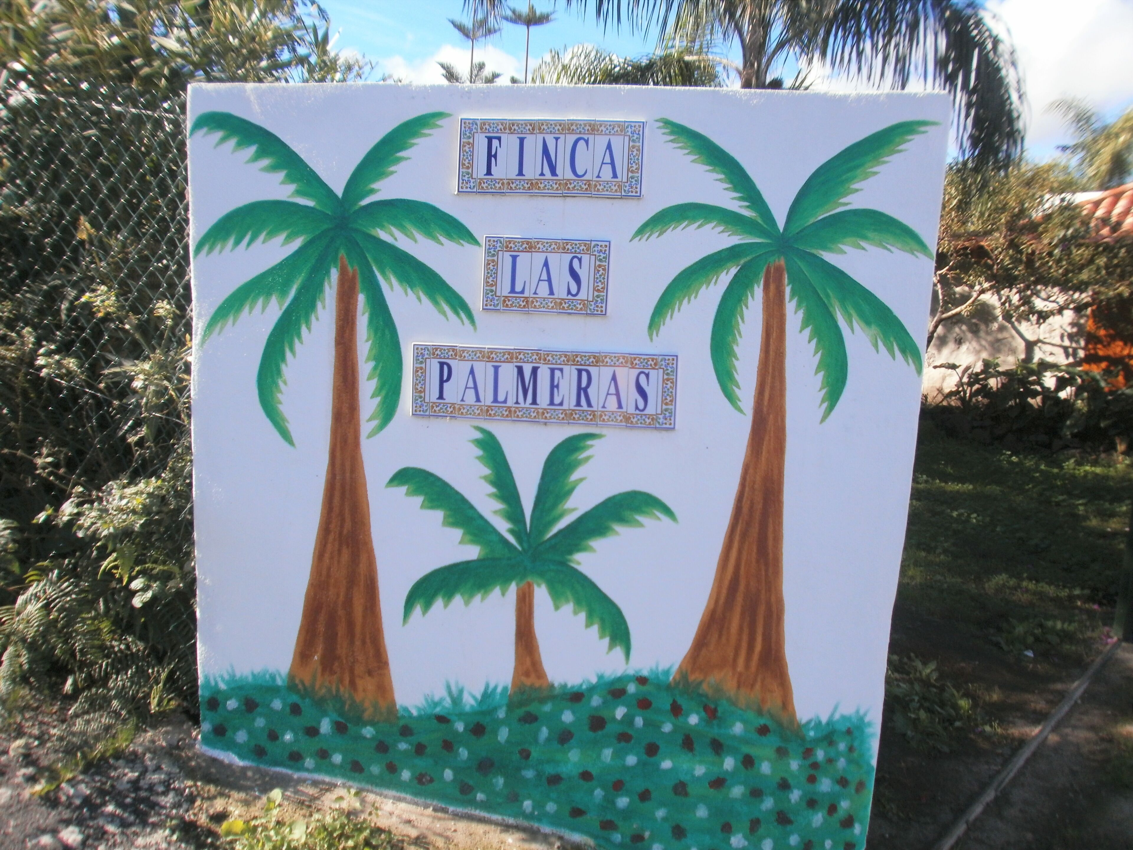 Ein Schild mit Palmen und dem Text 'FINCA LAS PALMERAS'.