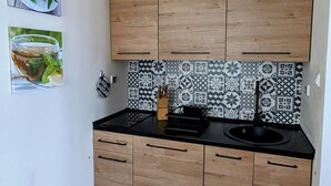 Une cuisine moderne avec des meubles en bois, un plan de travail noir et des carreaux décoratifs pour le dos de l’évier.