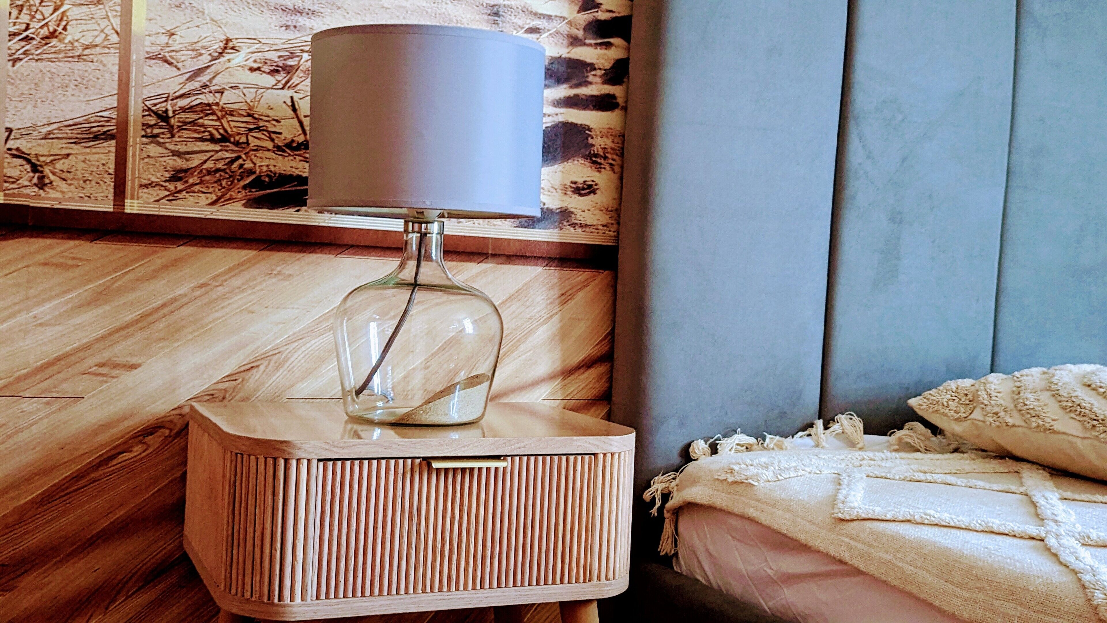 A wooden bedside table with a lamp and a decorative item on it.