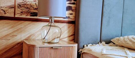 A wooden bedside table with a lamp and a decorative item on it.