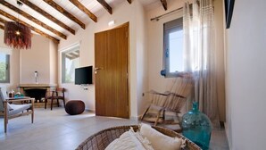 A living room with a fireplace, a television, and a large window with curtains. - Rea's Sea House with private pool (10m x 4m) (Galatas)