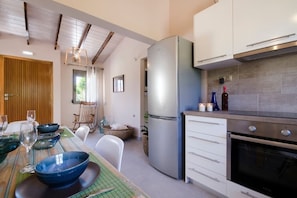 A modern kitchen with a stainless steel refrigerator, white cabinets, and a built-in oven.