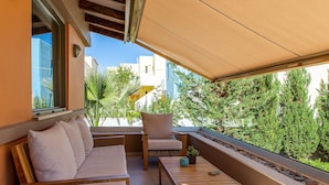 A balcony with a sofa, chairs, a small table, and a wicker stool. - Rea's Sea House with private pool (10m x 4m) (Galatas)