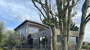 Een modern huis met twee verdiepingen, een groot raam en een verzorgd gazon.