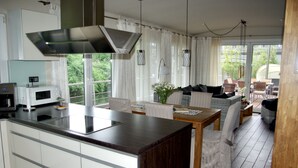 Une cuisine moderne dotée d’un îlot central, de meubles blancs et d’un coin repas avec une table et des chaises.