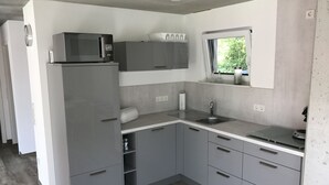 Una cocina compacta con armarios grises, un microondas integrado, una ventana con vistas y un lavamanos.