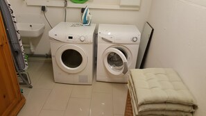 Un cuarto de lavandería con dos lavadoras, una secadora y una pila de toallas dobladas.