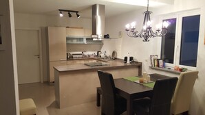 Une cuisine moderne dotée d’un îlot central, d’appareils électroménagers en acier inoxydable et d’un lustre.