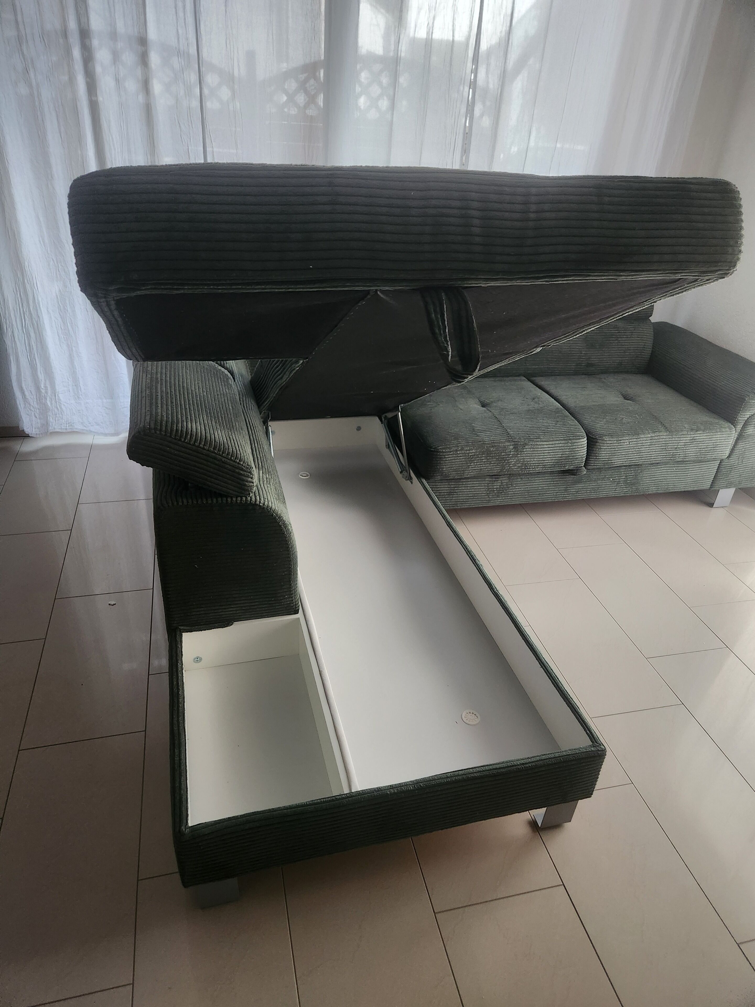 A modern sofa with a pull-out desk in a bright room with white curtains.