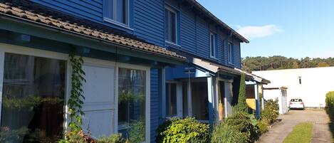 A blue house with a tiled roof, large windows, and a covered porch.