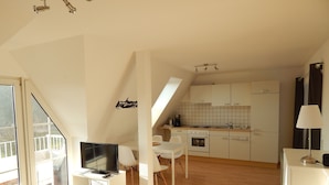 A modern apartment with a kitchen, dining area, and a TV in the living room. - Cozy 1 bedroom apartment with water views (Harrislee)
