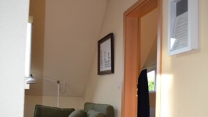 A room with a wooden floor, a green sofa, a lamp, and a door leading to another room. - Pferdehof Muhlitz on Rügen, an idyll for individualists (Samtens)