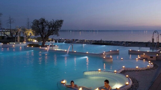 A swimming pool with hot tubs and lights at dusk. - Casa Bella: A charming apartment with a beautifully overgrown garden (Bardolino)