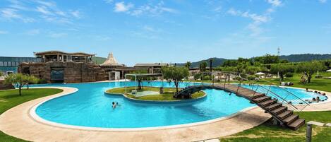 A swimming pool with a curved design, a covered area, and a bridge leading to a hot tub.