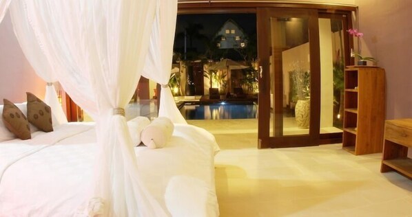 Un dormitorio con cama, mesita de noche y vistas a una piscina y zona exterior.