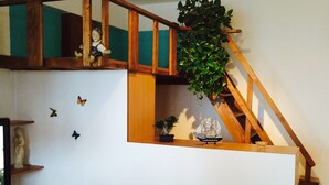 Une pièce avec un escalier en bois, un bureau avec un ordinateur portable, une chaise et une plante.