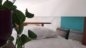 Un lit avec une literie blanche, une tête de lit en bois et des oreillers à rayures.