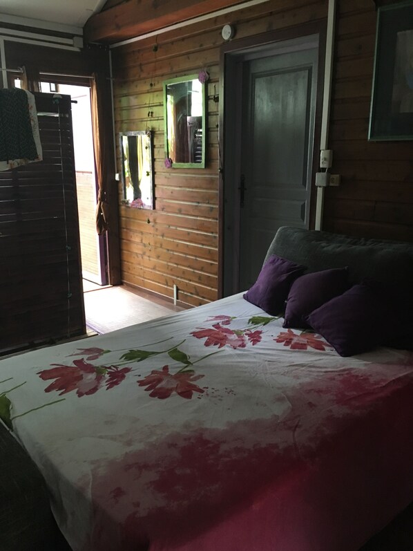 A room with a bed, a door, and a mirror on the wall.