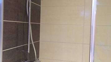 A shower with a handheld showerhead and a wall-mounted control panel.