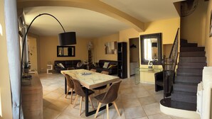 Uma sala de estar ampla com uma mesa de jantar, sofás e uma escada.
